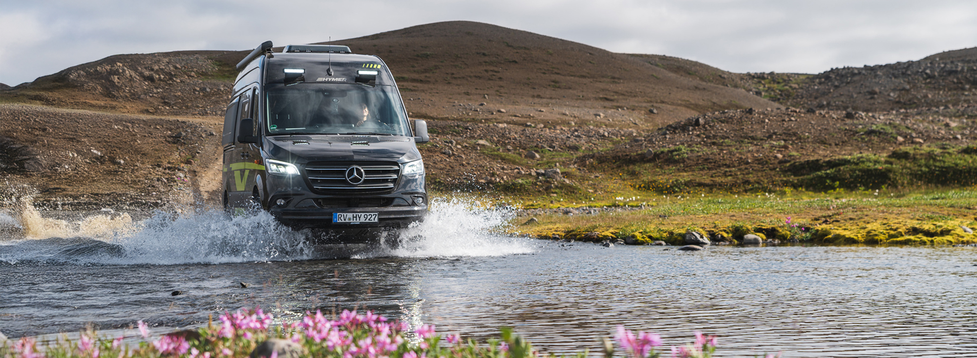 Eine Frau fährt einen Offroad-Kastenwagen durch einen Fluss.