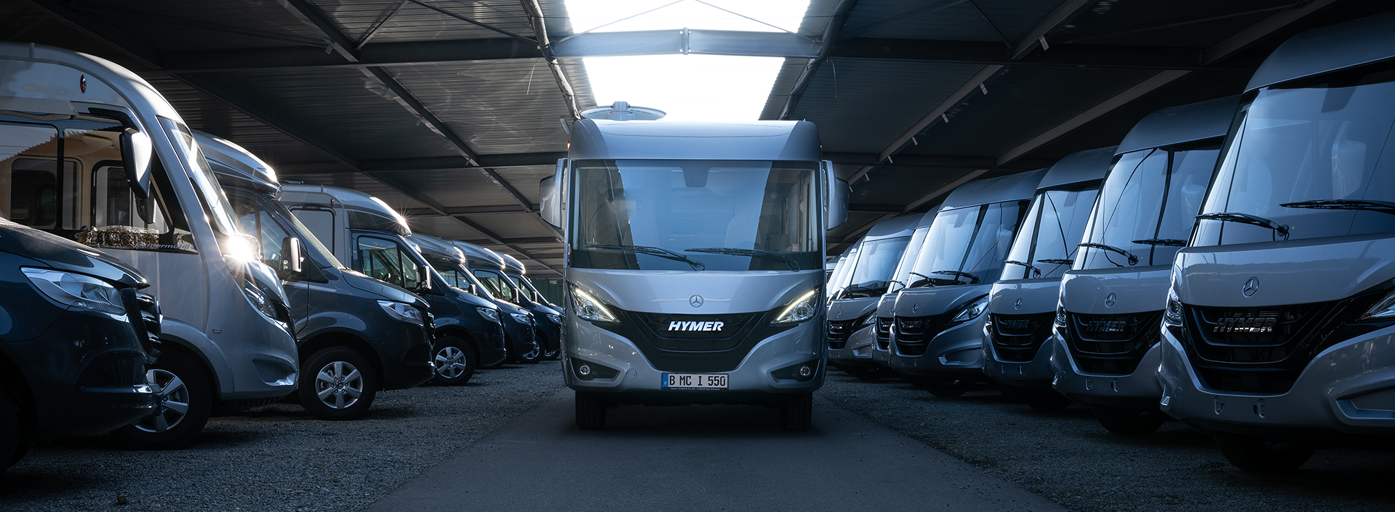 Mehrere Wohnmobile stehen in einer Industriehalle.
