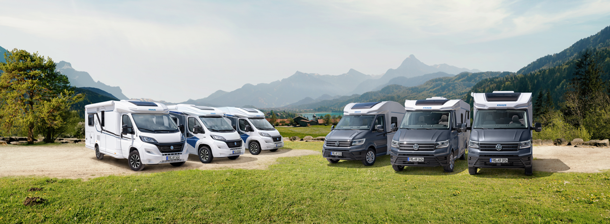 Diverse Wohnmobile von KNAUS stehen auf einer Wiese.