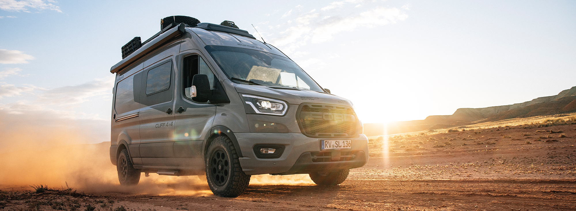 Ein Kastenwagen von Sunlight fährt im Gegenlicht durch eine Wüste.