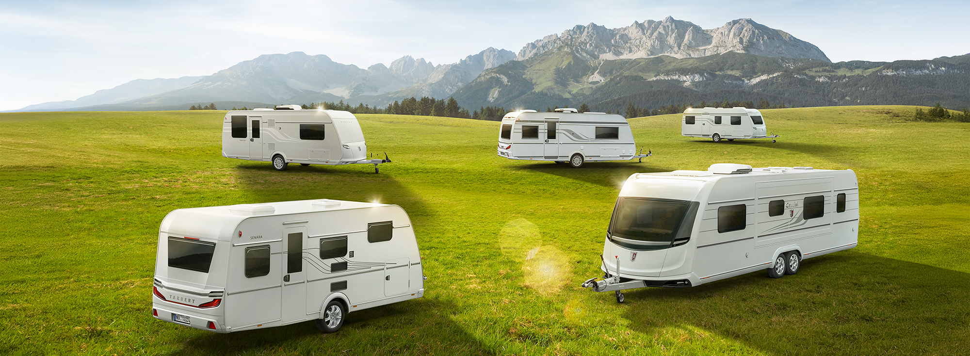 Mehrere Caravans stehen auf einer grünen Wiese.