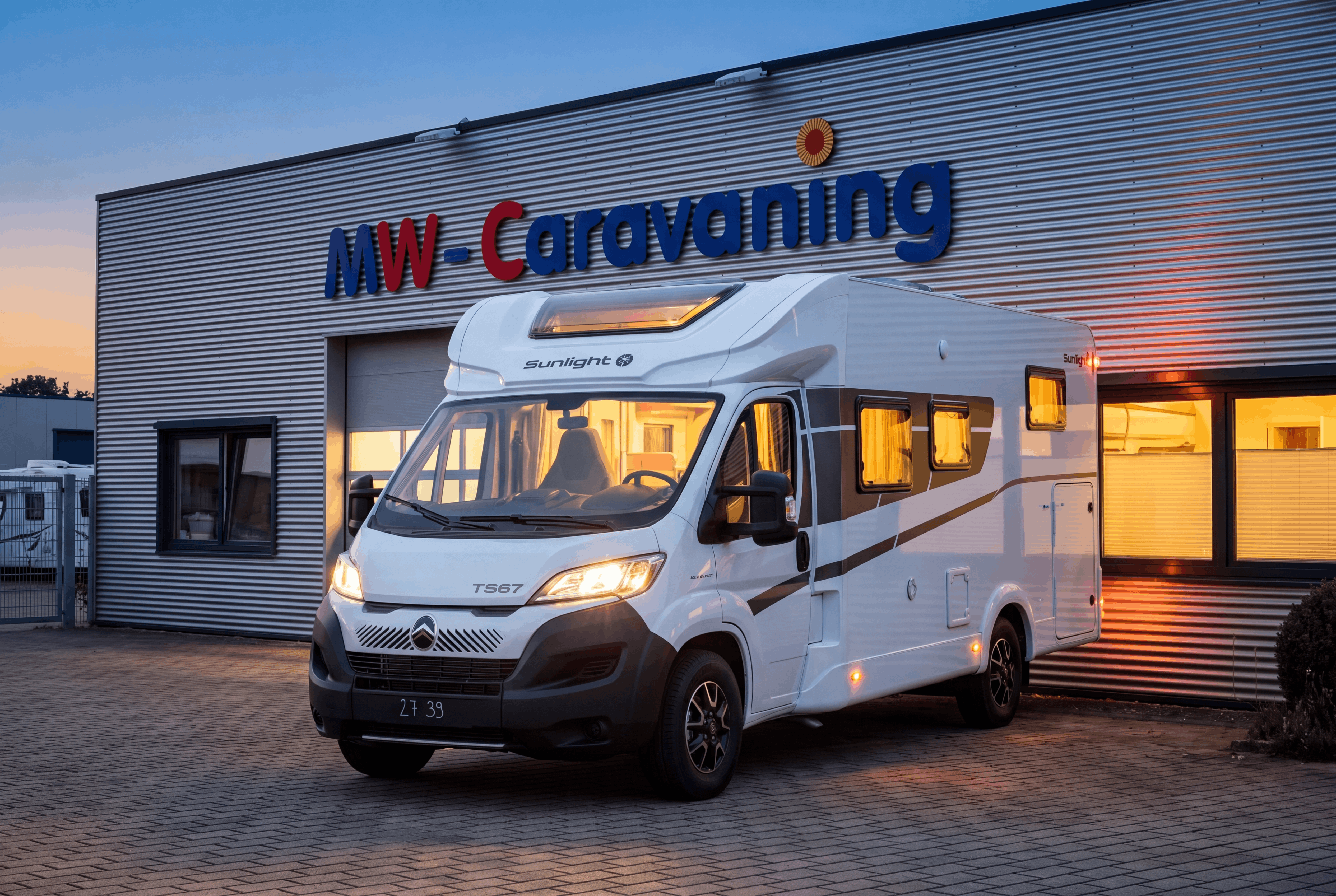 Beleuchtetes Wohnmobil in der Abenddämmerung vor dem Gebäude von MW-Caravaning in Möttingen.